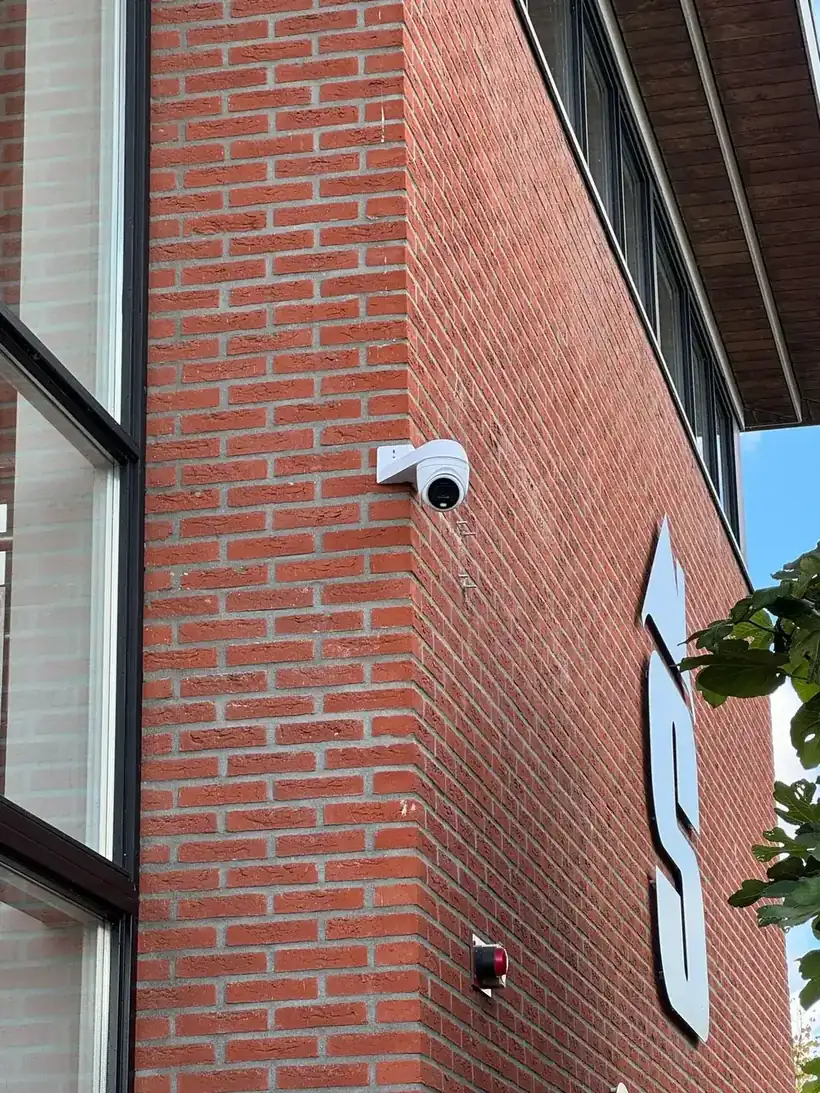 Beveiligingscamera gemonteerd aan de bakstenen gevel van een bedrijfspand