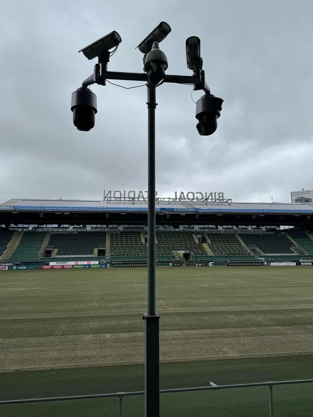 Cameramast met vijf camera's langs de rand van een sportveld in een stadion
