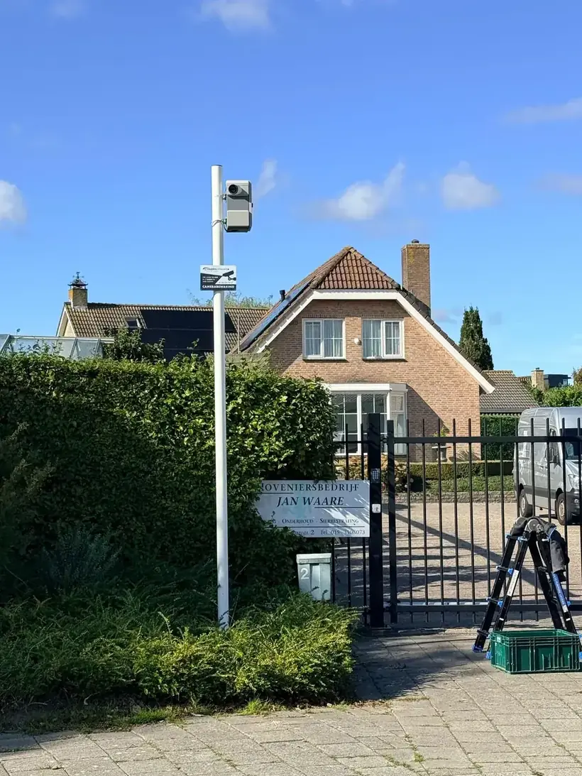 Camerapaal bij de gesloten poort en het hekwerk van een terrein