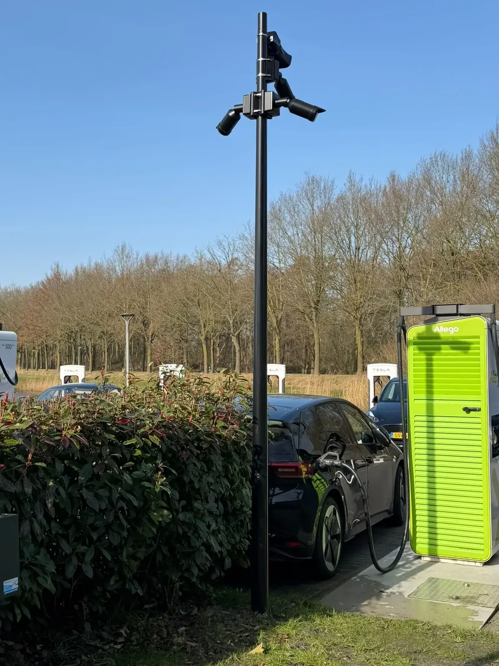 Camerapaal met camerakop boven een laadplein met opladende auto's