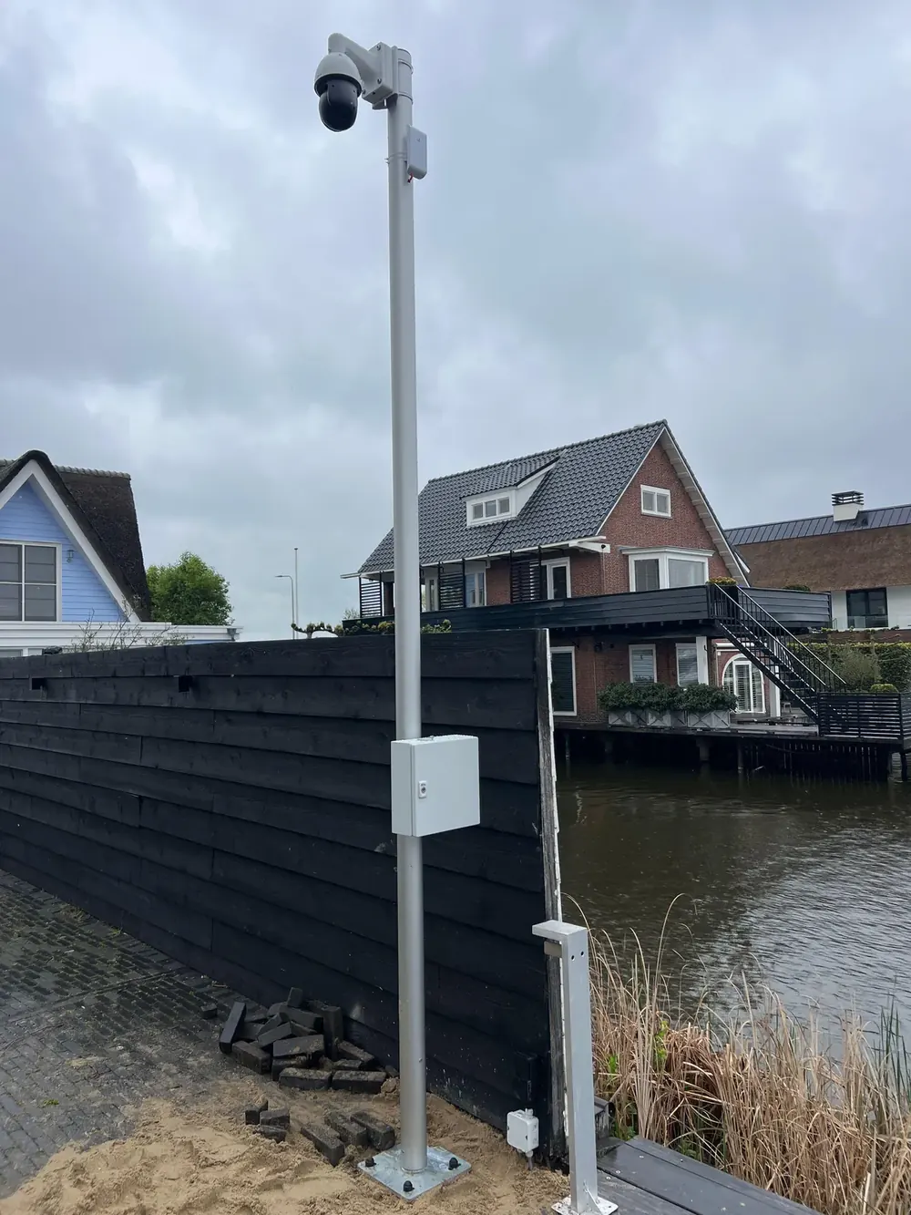 Camerapaal met aansluitkast langs een beschoeiing aan het water