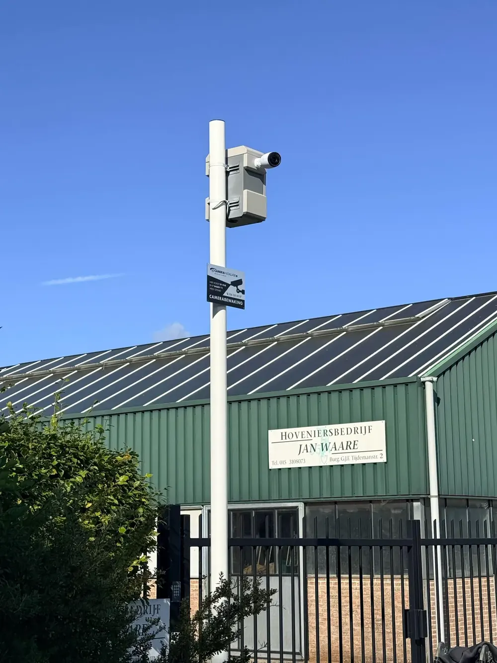 Camerapaal met camera en kast voor de loods van een bedrijfsterrein