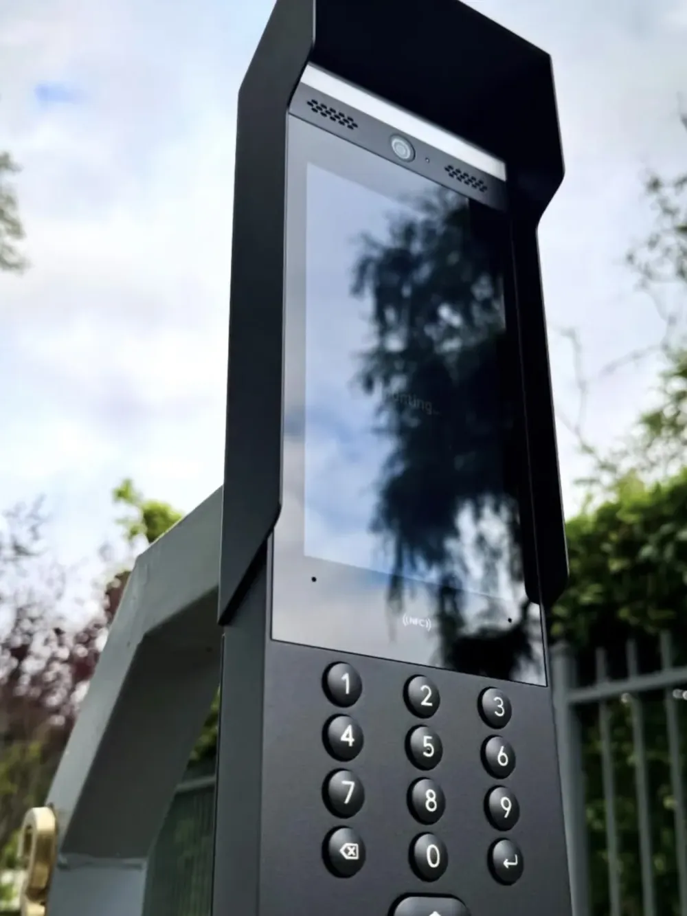 Intercom met toetsenbord en camera op een paal bij het hek van een terrein