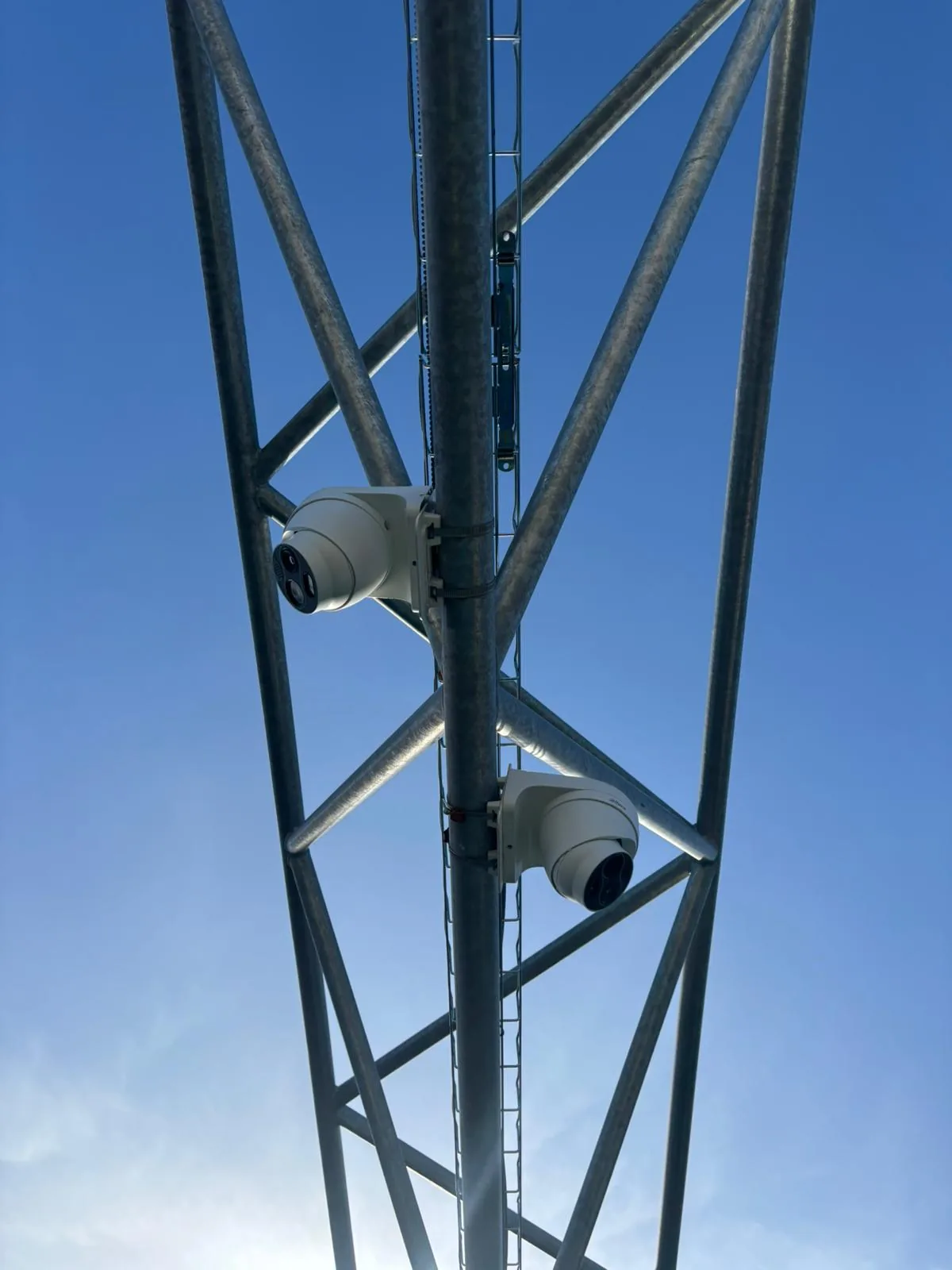 Twee beveiligingscamera's gemonteerd aan een vakwerkmast op een buitenterrein